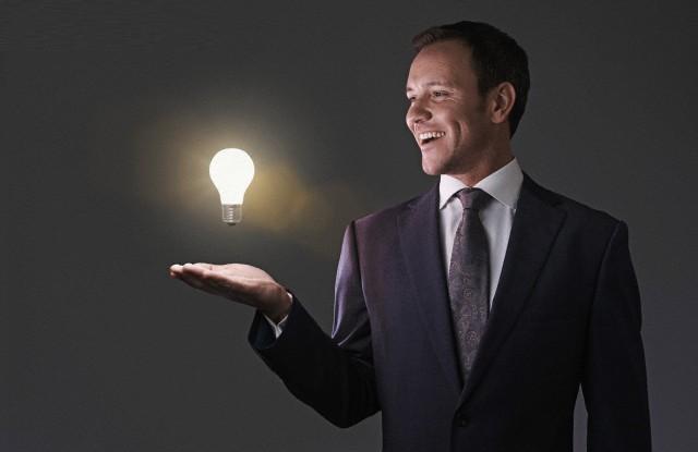 Portrait of mid adult man with illuminated light bulb --- Image by © Matt Bird/Corbis